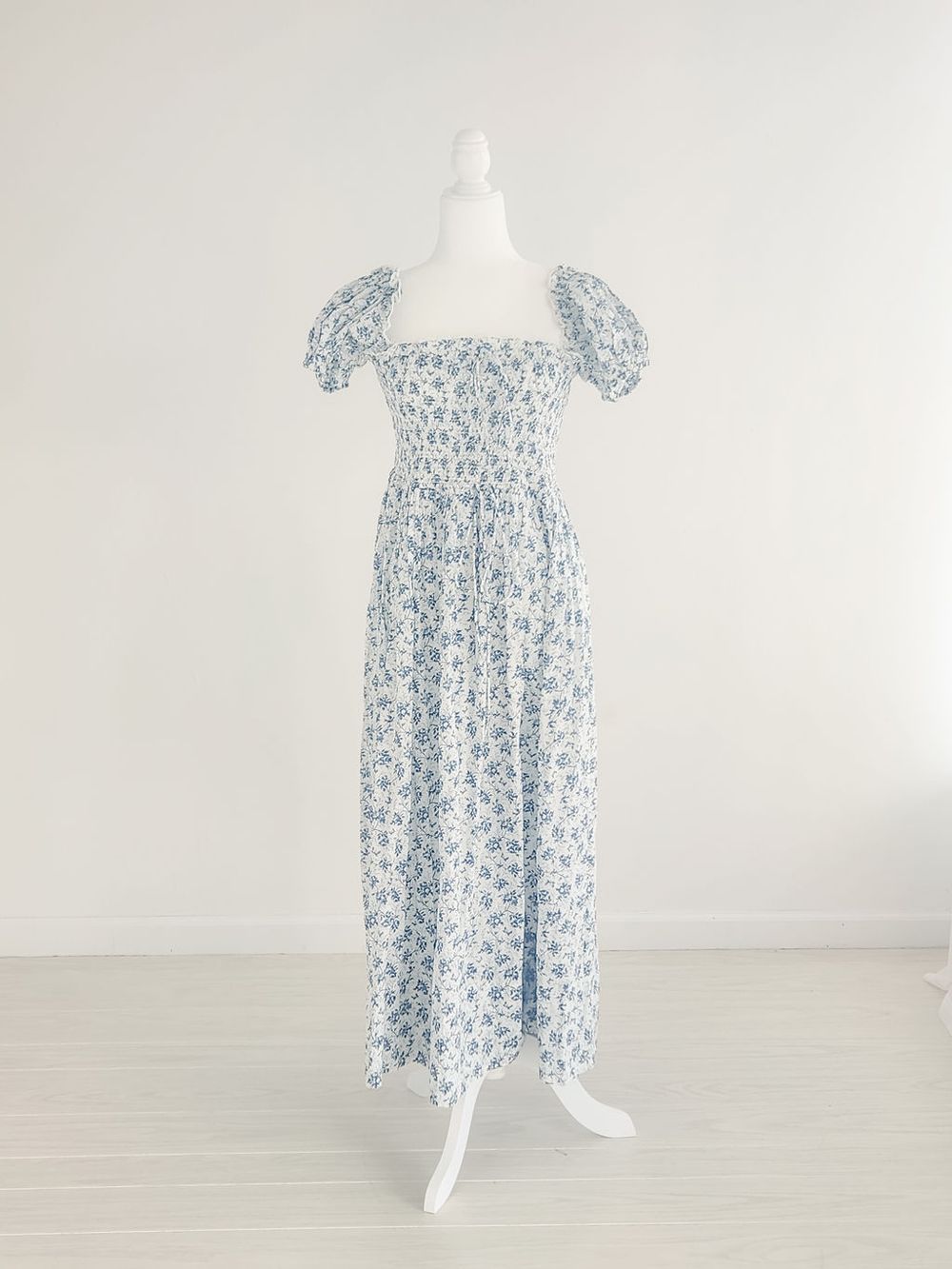 Light blue floral print smocked sundress displayed on white mannequin against neutral background.