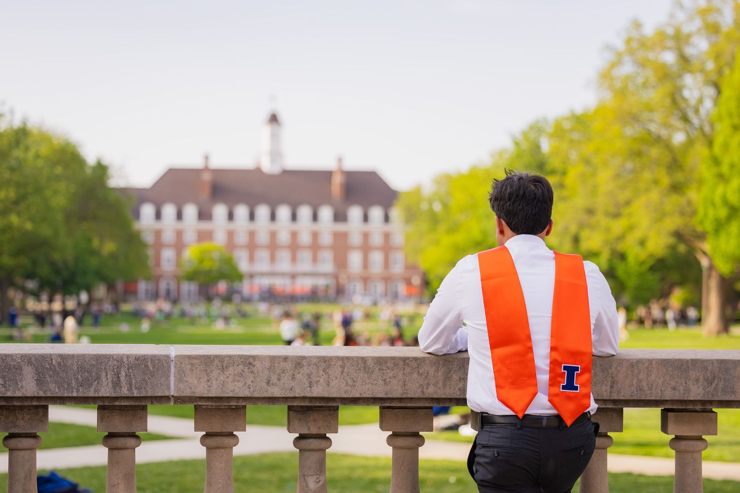 Student at UIUC looking at the Illini Union and Main Quad with graduation attire