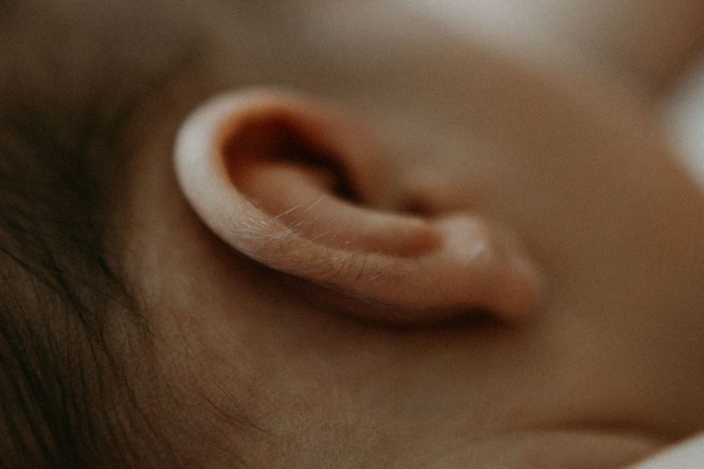 Tarkka lähikuva vastasyntyneen korvasta ja korvakarvoista perheen kotona postpartum- ja vauvakuvauksessa.