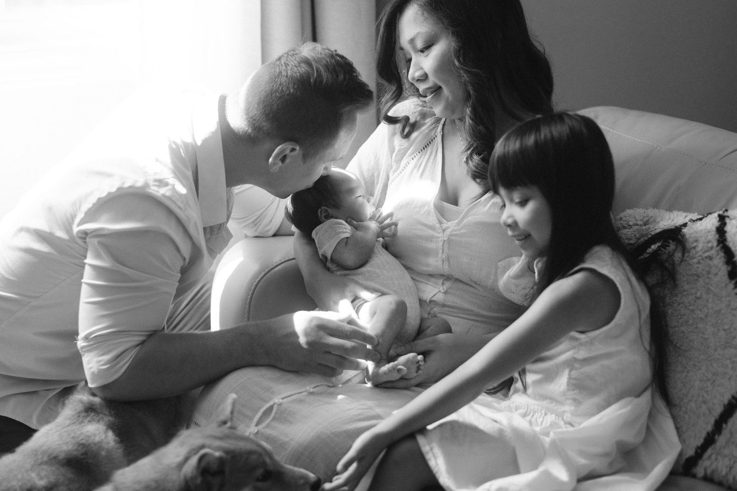 A cozy home photography session for a family with a newborn baby and dogs.
