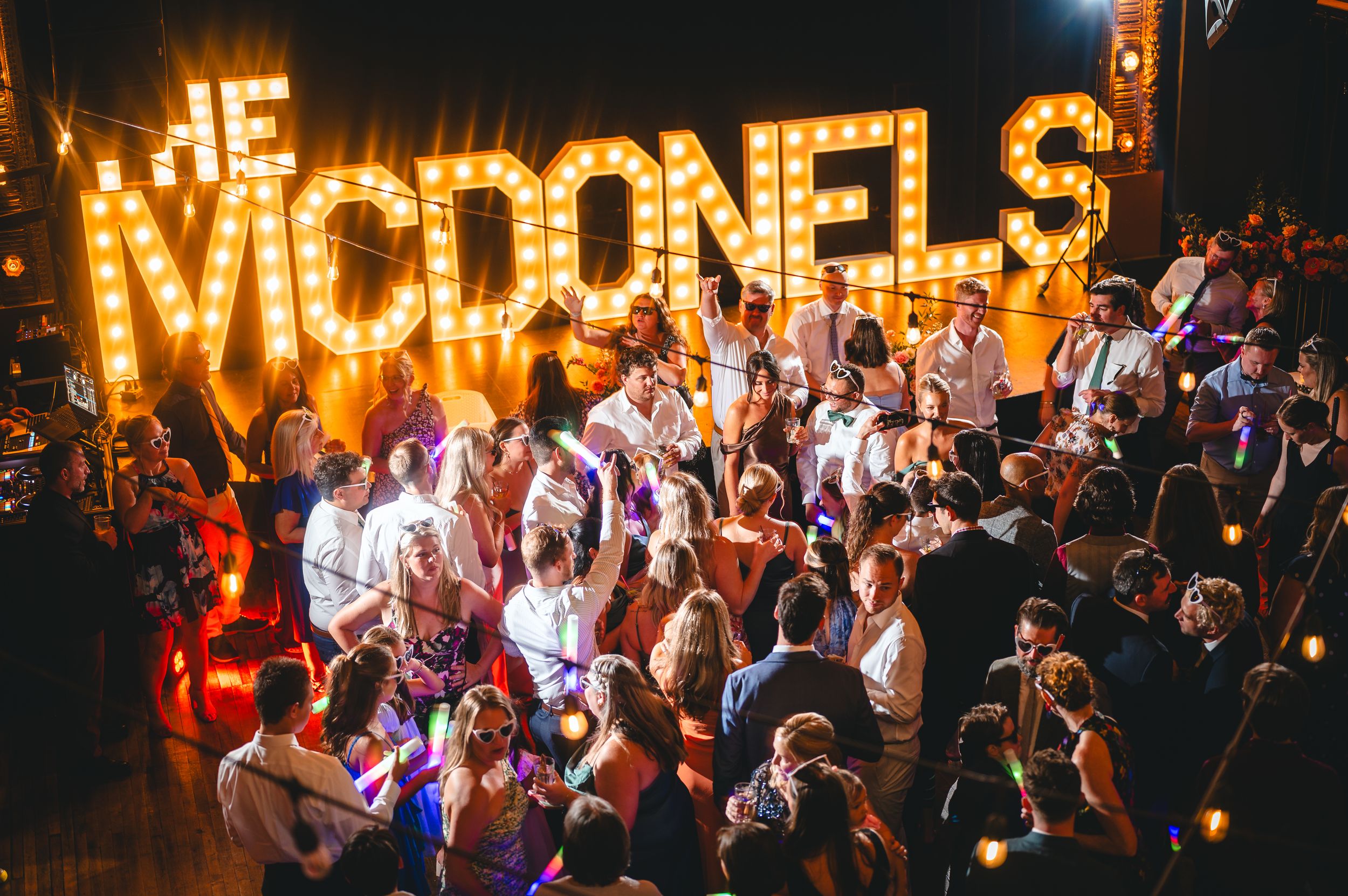 A crowd dances beneath illuminated marquee letters spelling 'THE MOTIONELS' at a nightclub performance.
