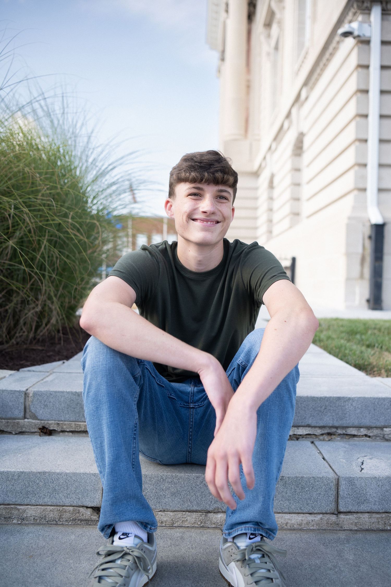 Portrait series of someone in a blue shirt against an ivy-covered brick wall background.