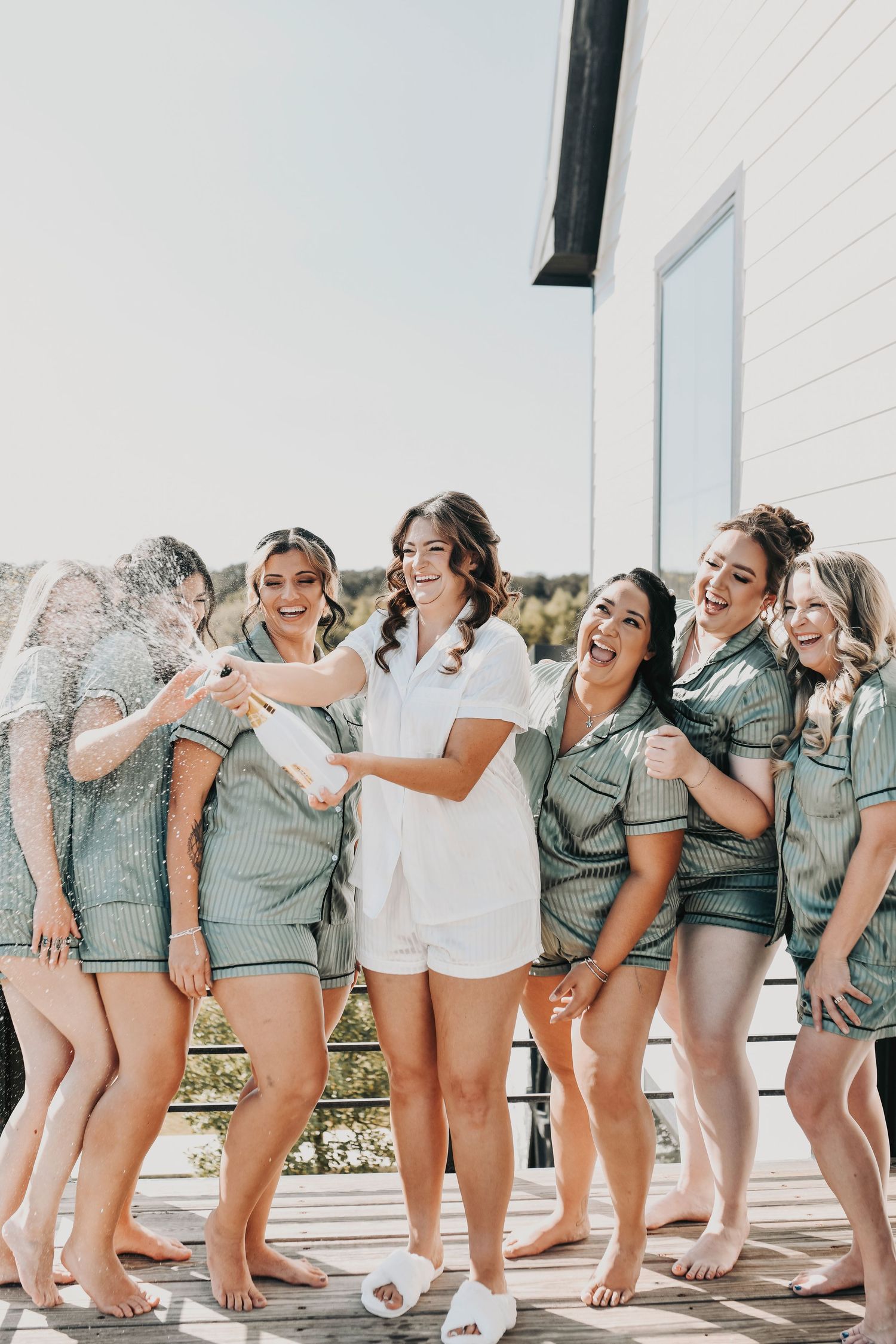 bride popping champagne with her bridal party