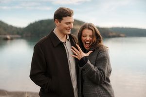 Couple shares joyful moments together while walking along a misty lakeside during an intimate outdoor photo session.
