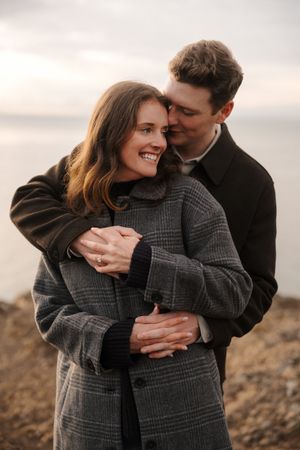 Romantic couple embracing outdoors wearing matching gray plaid coats in a series of intimate candid moments.