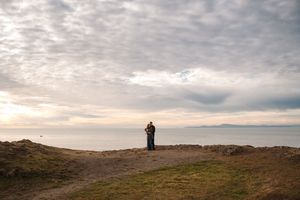 A panoramic view of a rugged coastal landscape with dramatic cloudy skies at sunset.