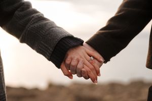 Two people shake hands in a formal business setting against a dark background.
