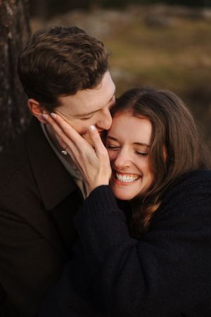 A romantic couple shares an intimate moment together in a dark outdoor setting with soft lighting and natural scenery.