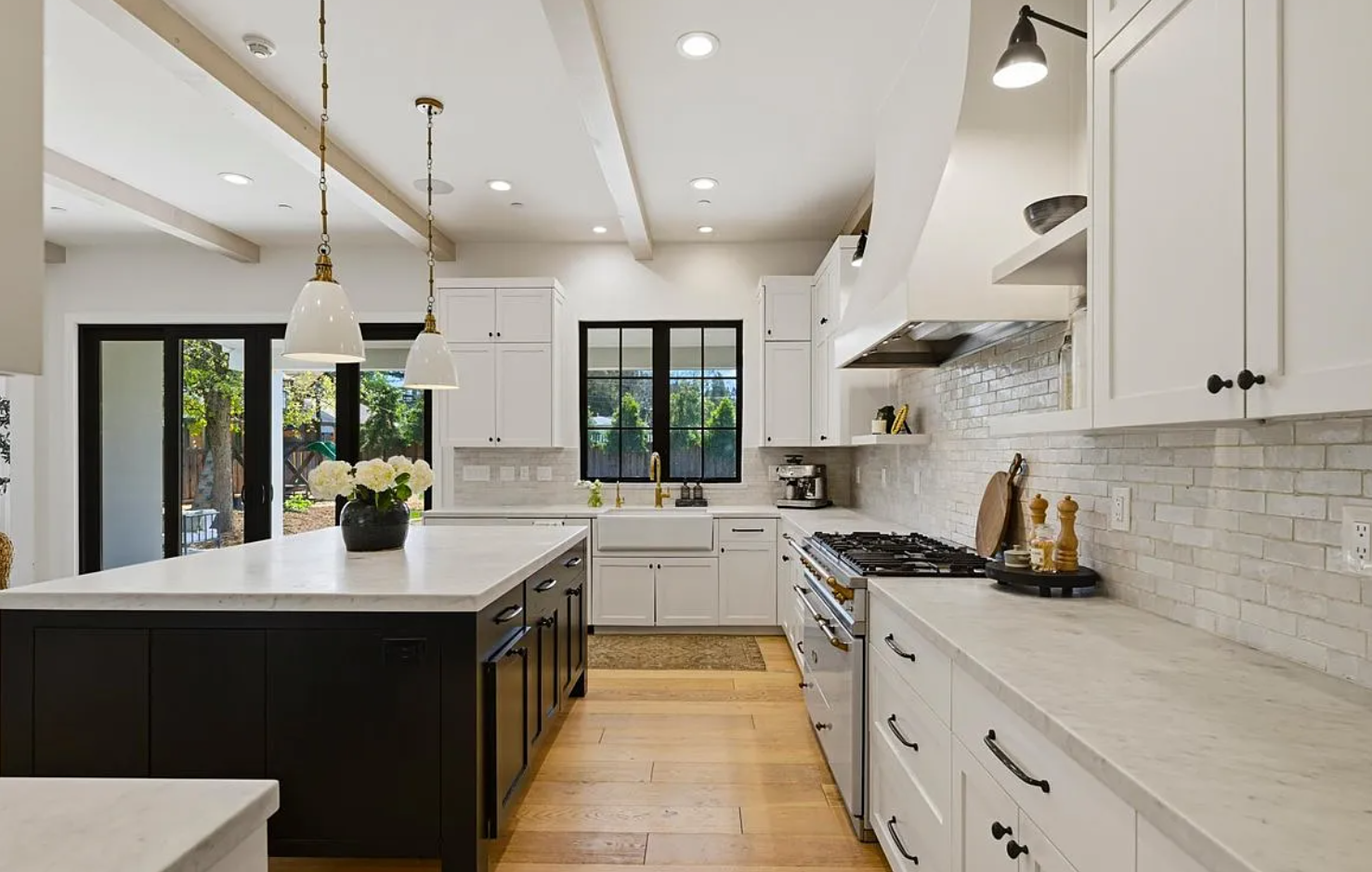 Modern white kitchen with subway tile backsplash, black hardware, and recessed lighting shows seamless design flow.