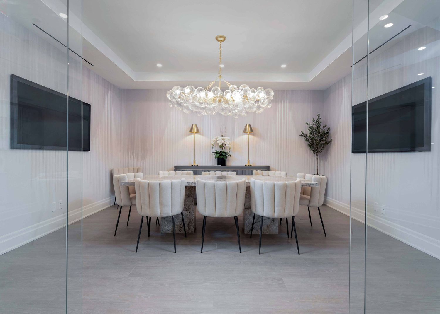 Modern white conference room with crystal chandelier, white chairs, and sleek minimalist design throughout.