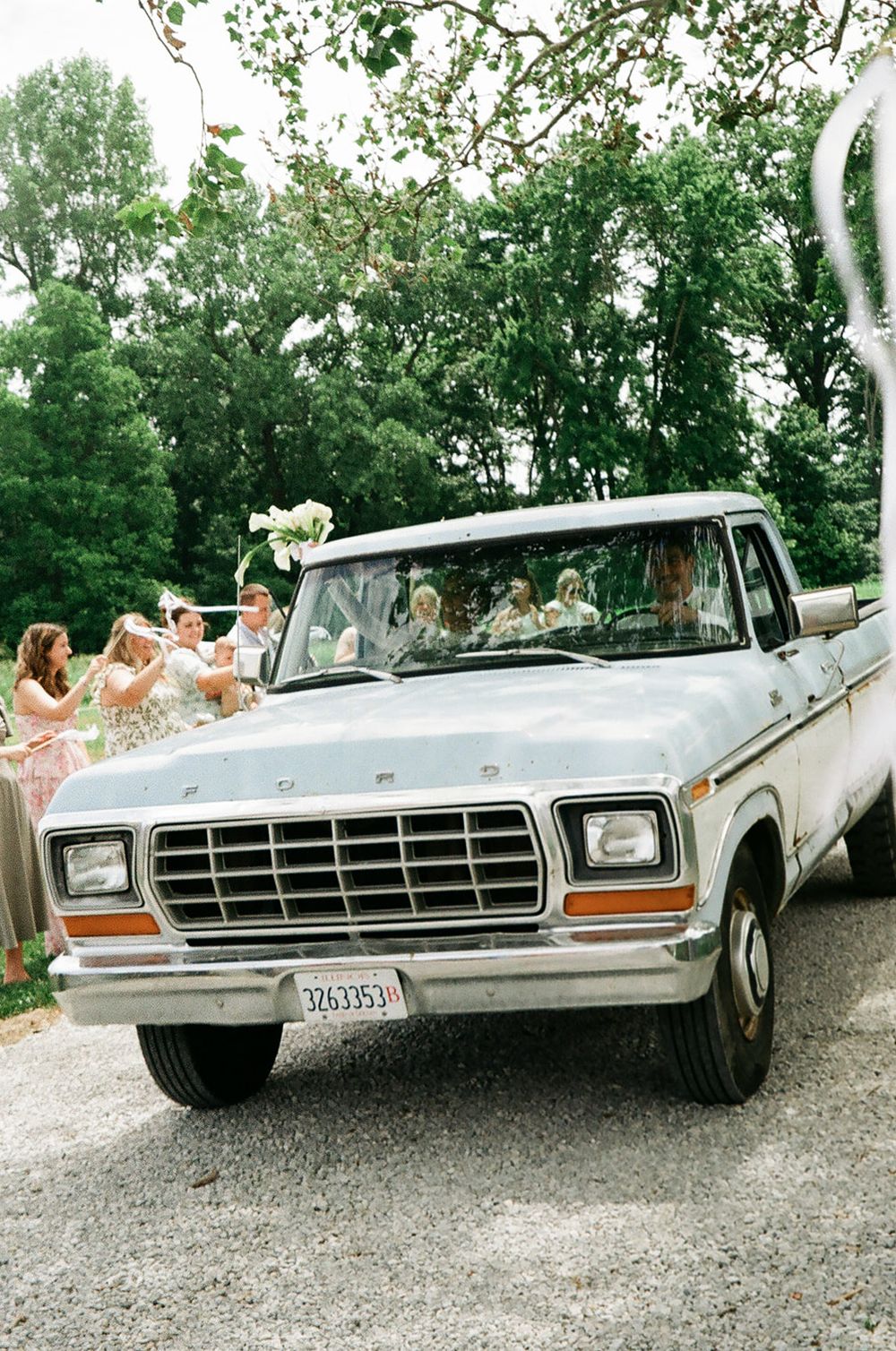 Vintage white Ford pickup truck at a wedding with bridesmaids in pink dresses holding bouquets outdoors.