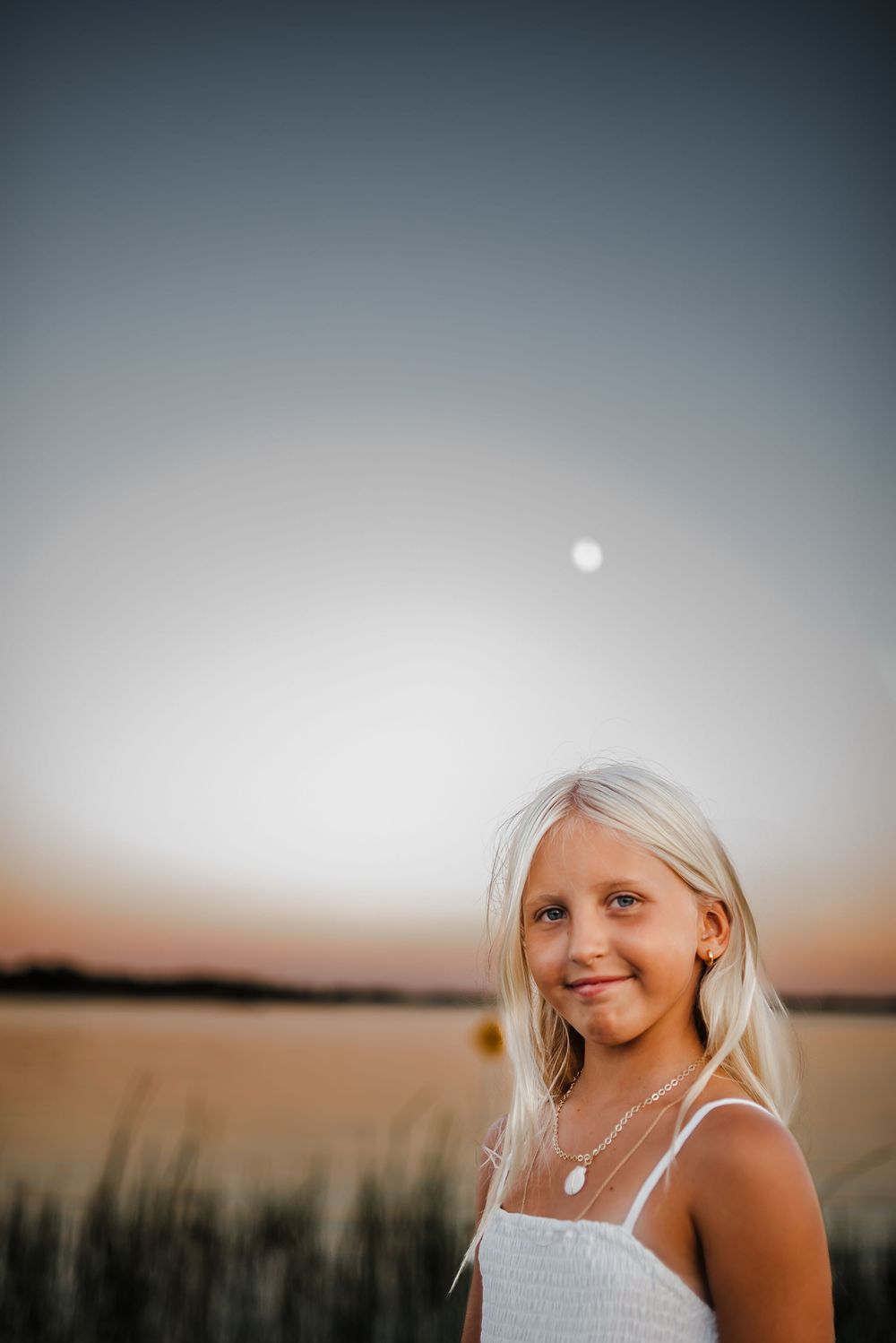 A series of sunset portraits showing a person with blonde hair in white clothing against a dusky sky background.