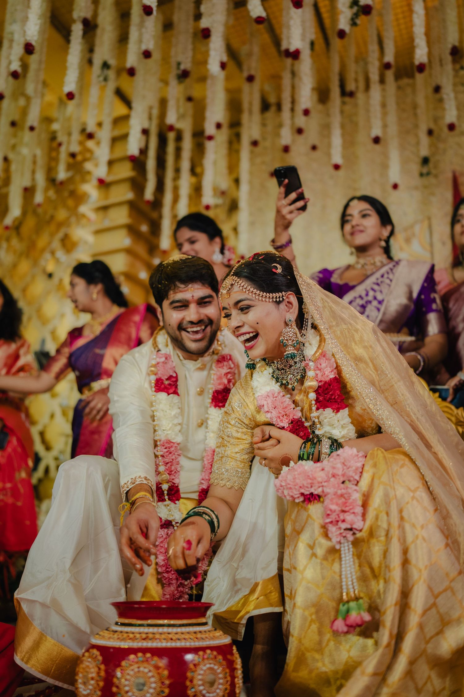 Indian bride and groom performing wedding ceremony ritual together in traditional golden attire with floral garlands.
