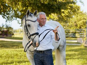 Mann führt sein Pferd auf der Weide. Professionelle Tierfotografie und authentische Aufnahmen der Lichtkapsel.