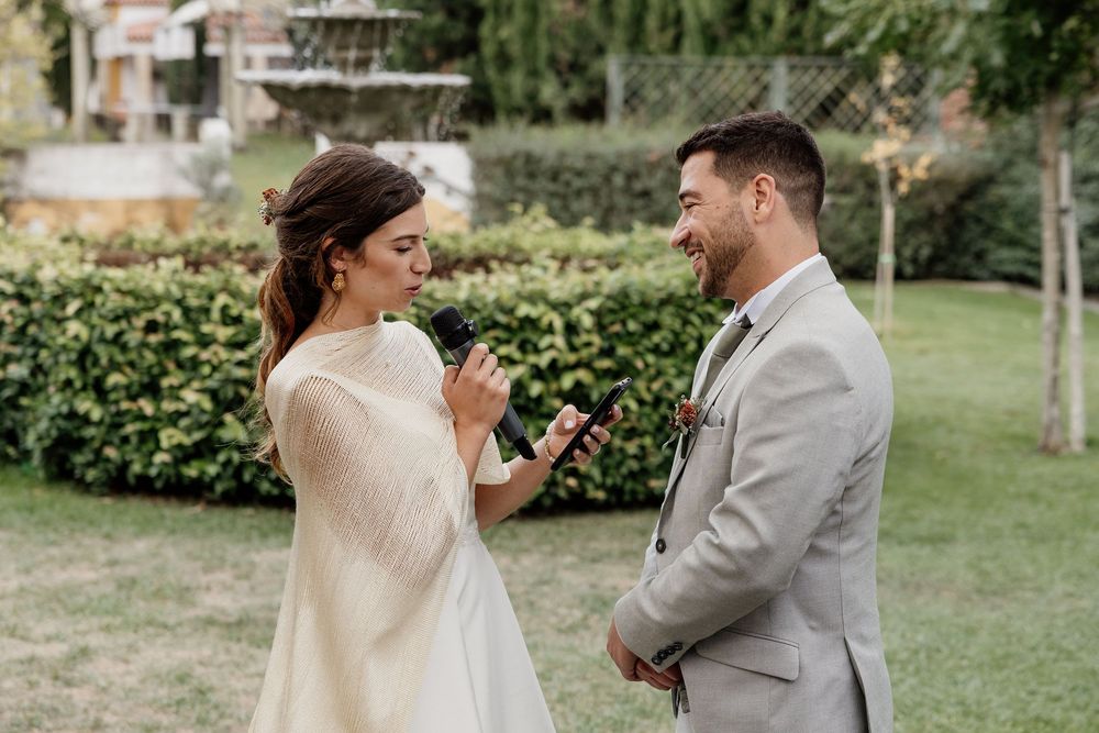 Bride and groom exchanging vows outdoors, smiling joyfully during their wedding ceremony in a lush garden.