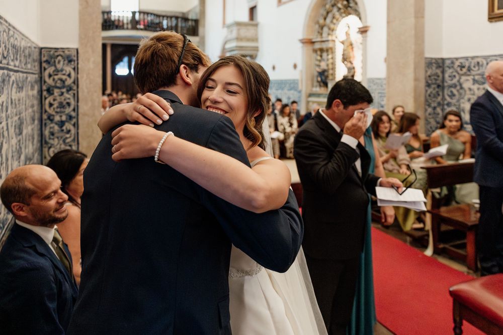 Bride and groom share a heartfelt hug during their wedding ceremony inside a beautiful church.