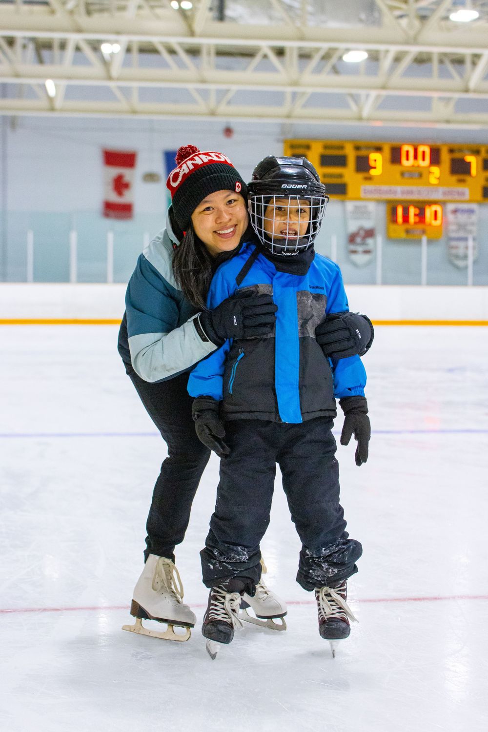 Ice skating lesson at indoor rink with red and white Canada hat and hockey equipment.