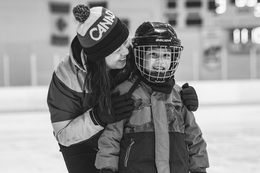 A hockey player in protective gear receives instruction from a coach on the ice rink during practice.