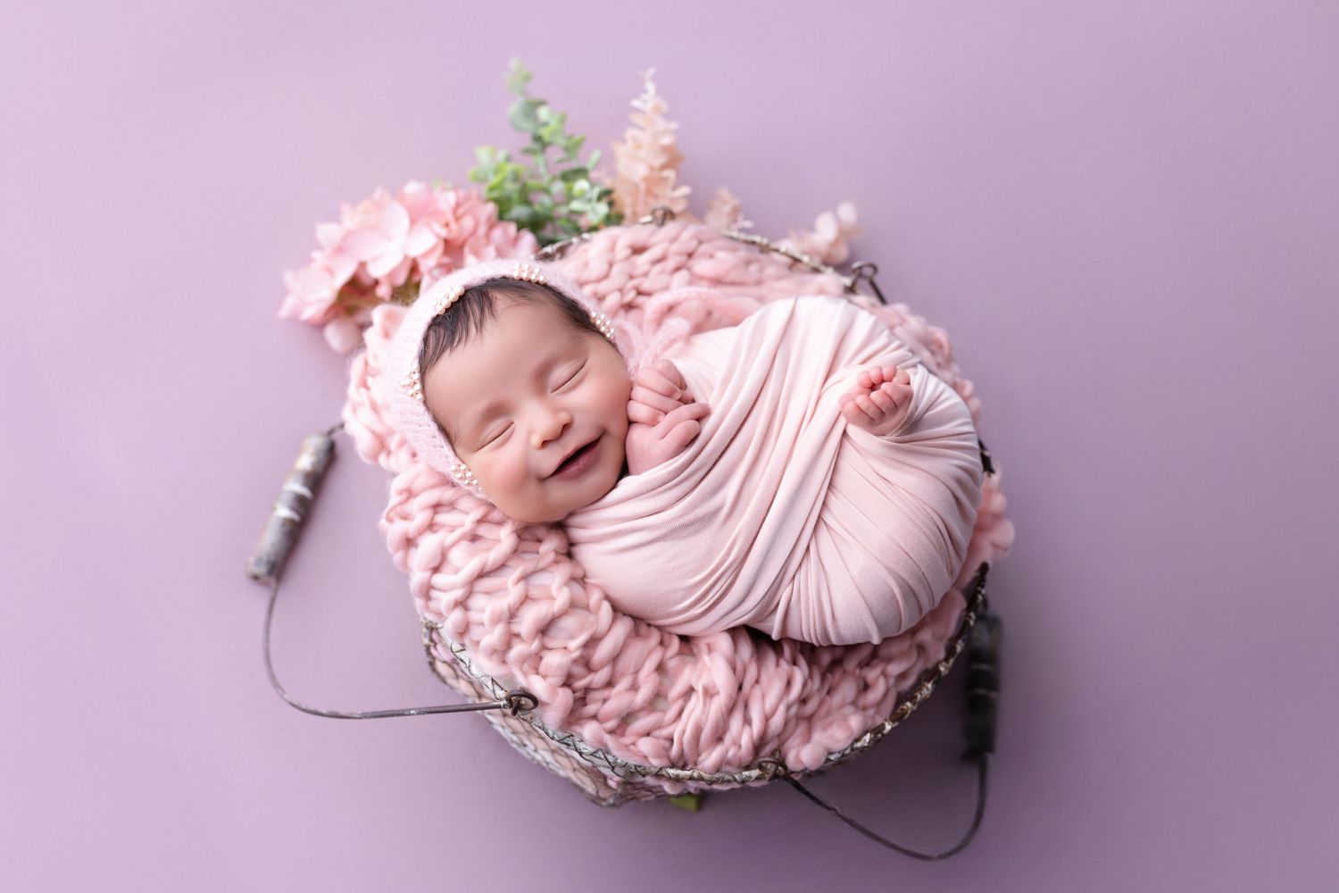 A collection of newborn photography portraits showing a sleeping baby wrapped in pink fabric on a purple backdrop.