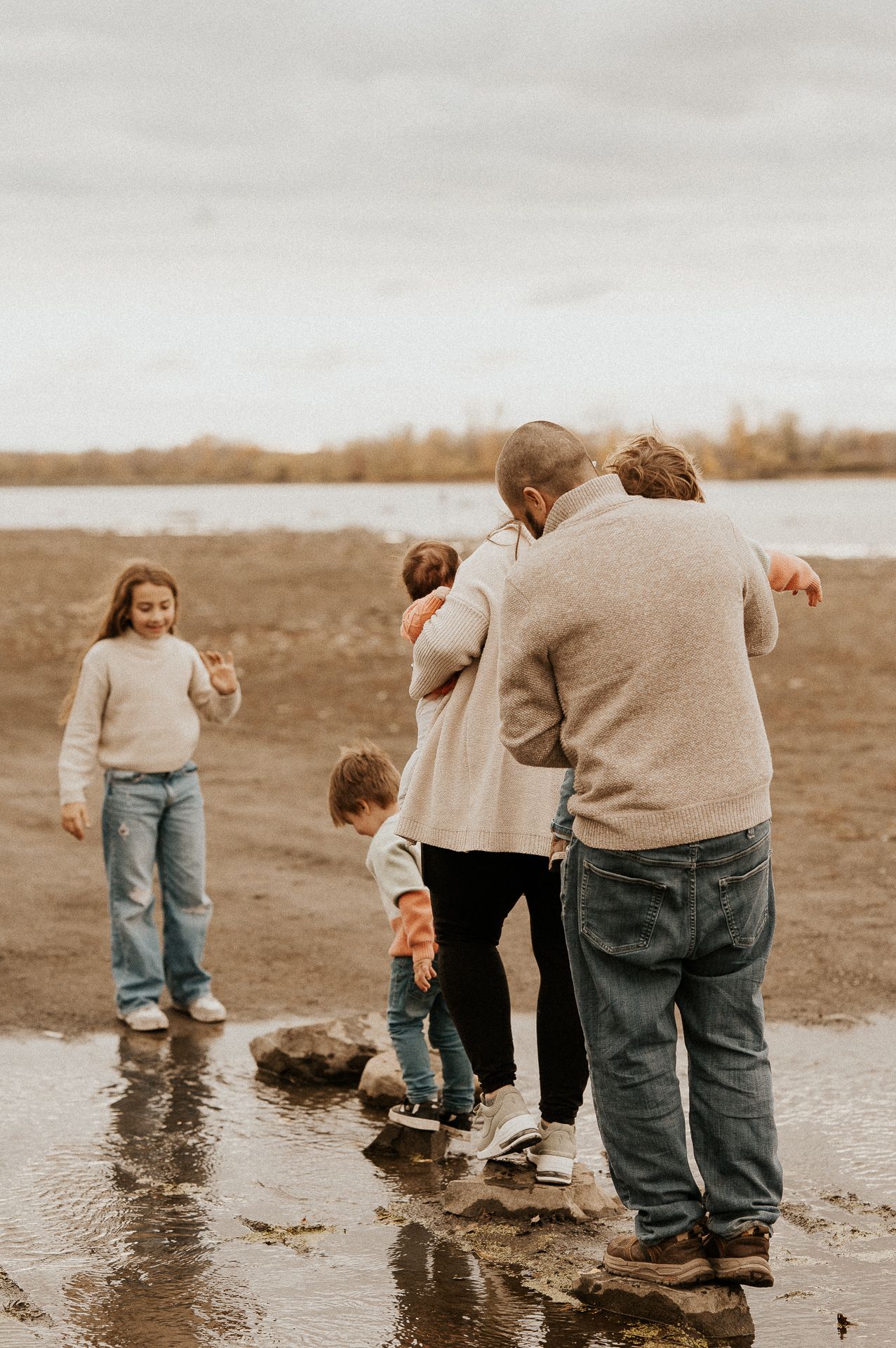 Deux adultes et deux enfants debout sur une rive, face à un plan d’eau. Séance famille Rive-Sud de Montréal.