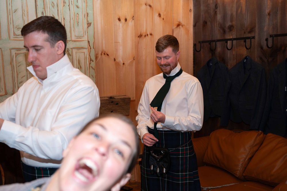 People in formal attire including white shirts and a kilt gather in a wood-paneled room during an event.