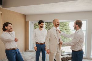 A group of men in casual and formal attire share a lighthearted moment while talking in a bright room.