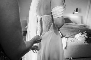 A person in a white wedding dress adjusts their gown while getting ready for their special day.