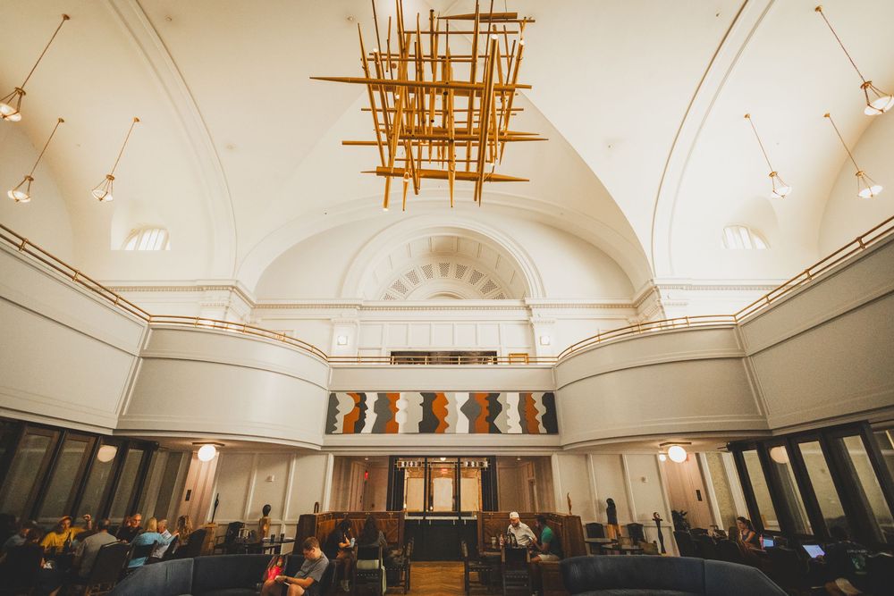 Interior of a grand church sanctuary with vaulted ceilings, ornate columns, and a modern geometric gold chandelier at the Line Hotel In DC