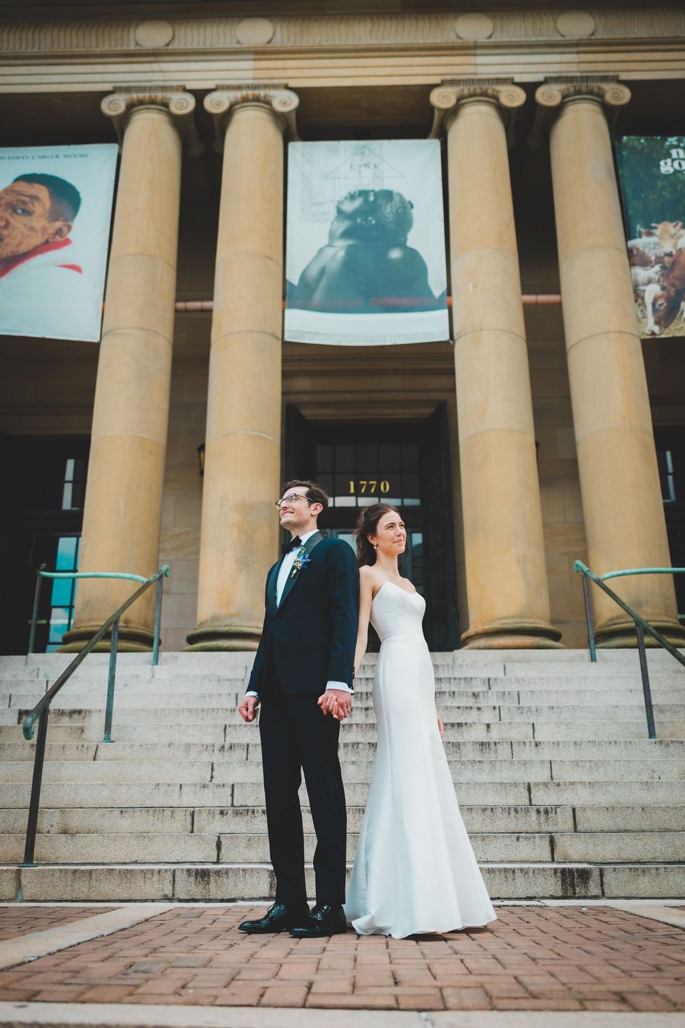 A couple poses elegantly on brick steps in front of a classical building with grand columns of the line washington DC