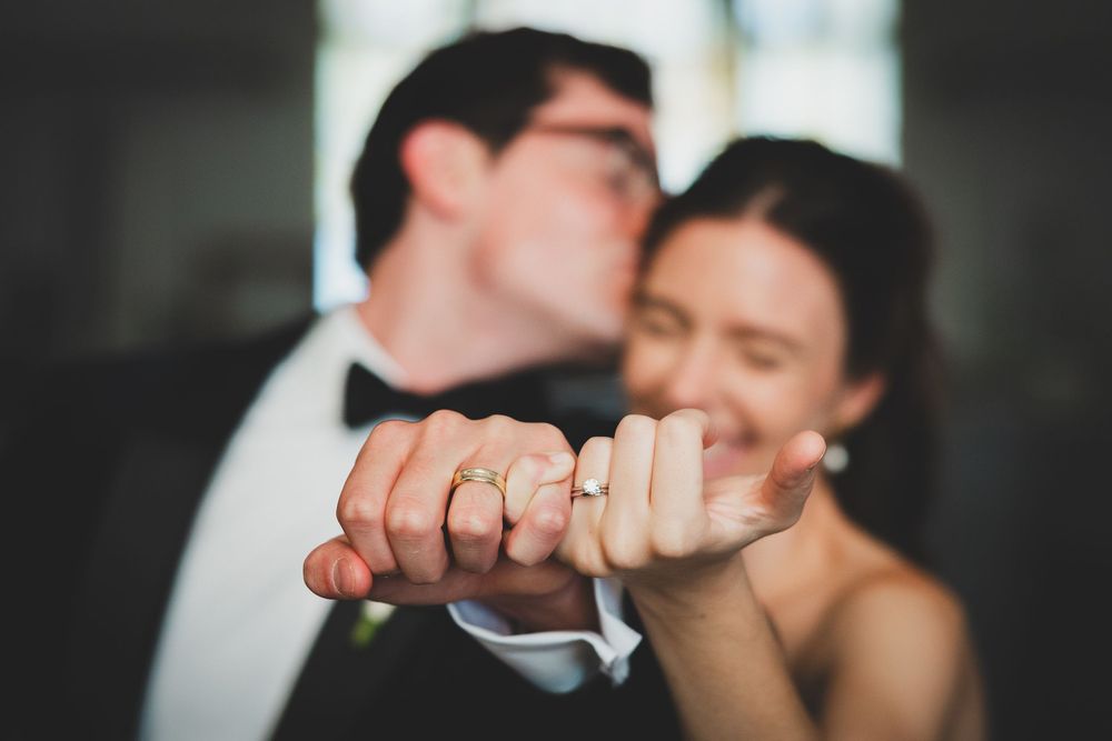 Close-up shot of newlyweds' hands clasped together while sharing a romantic moment during their wedding celebration.