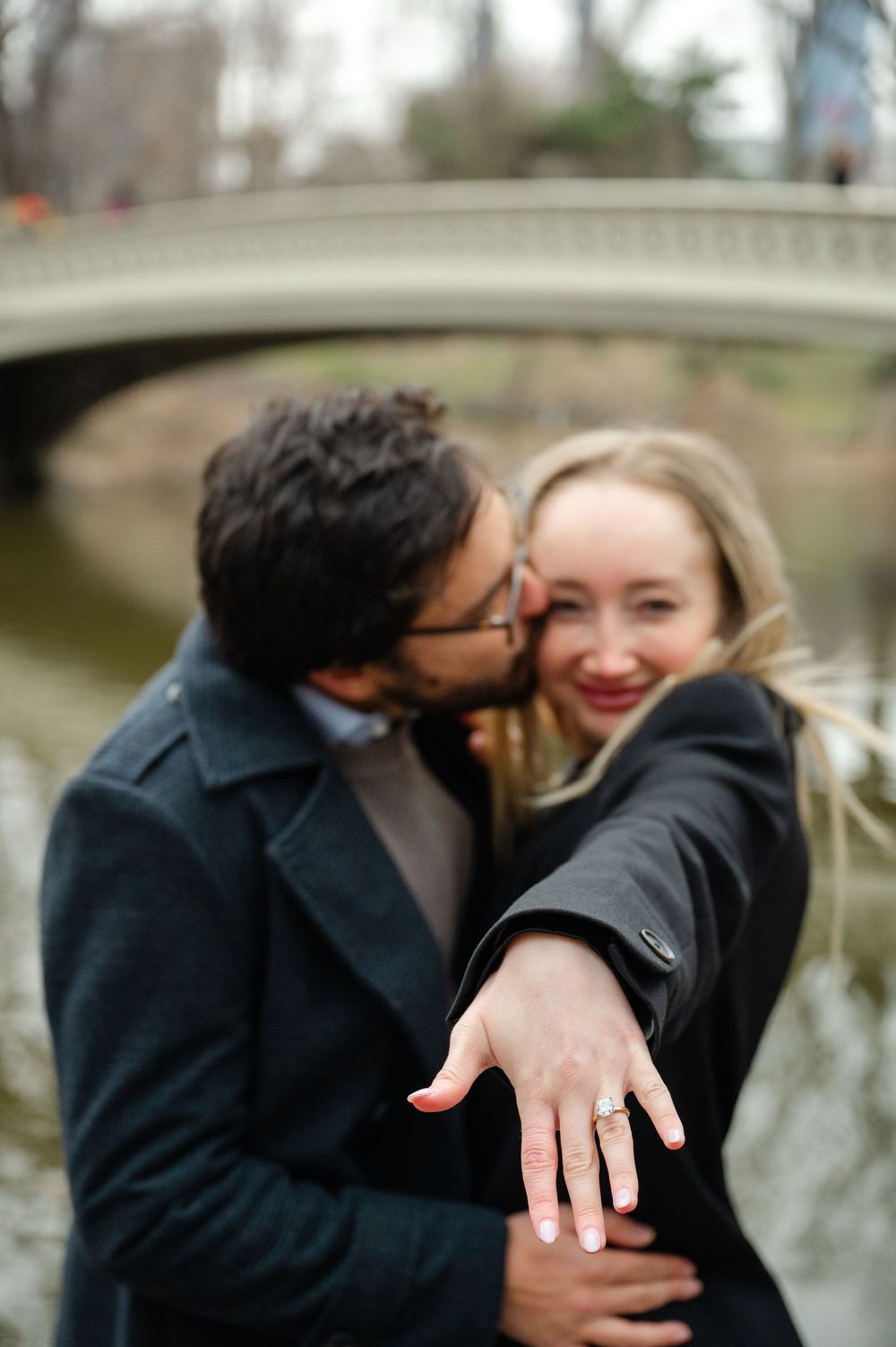 A romantic engagement photo series showing a couple embracing and displaying a new ring by a lake.