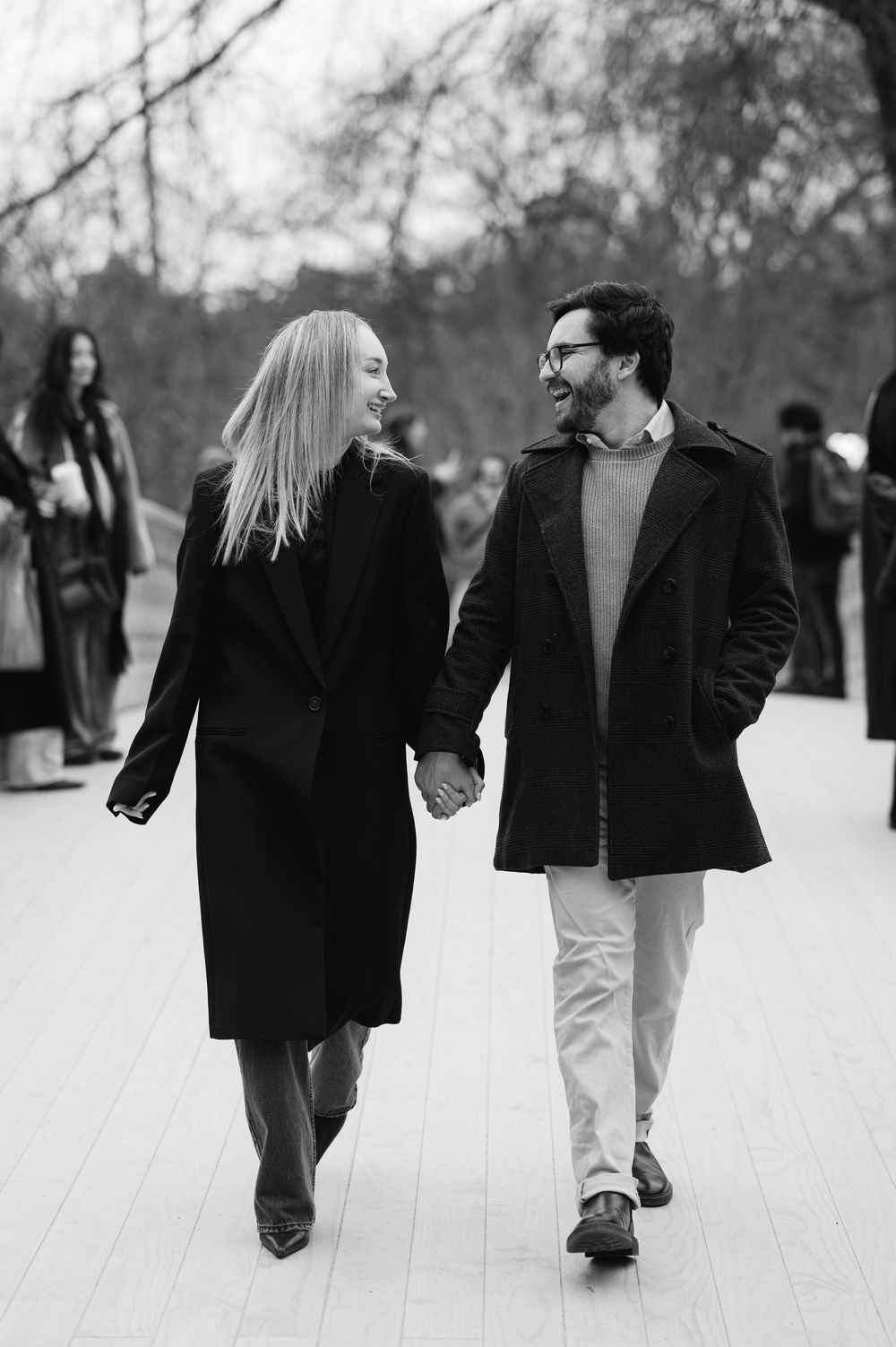 A couple walking together through a snowy winter scene in black and white, shown from multiple angles.