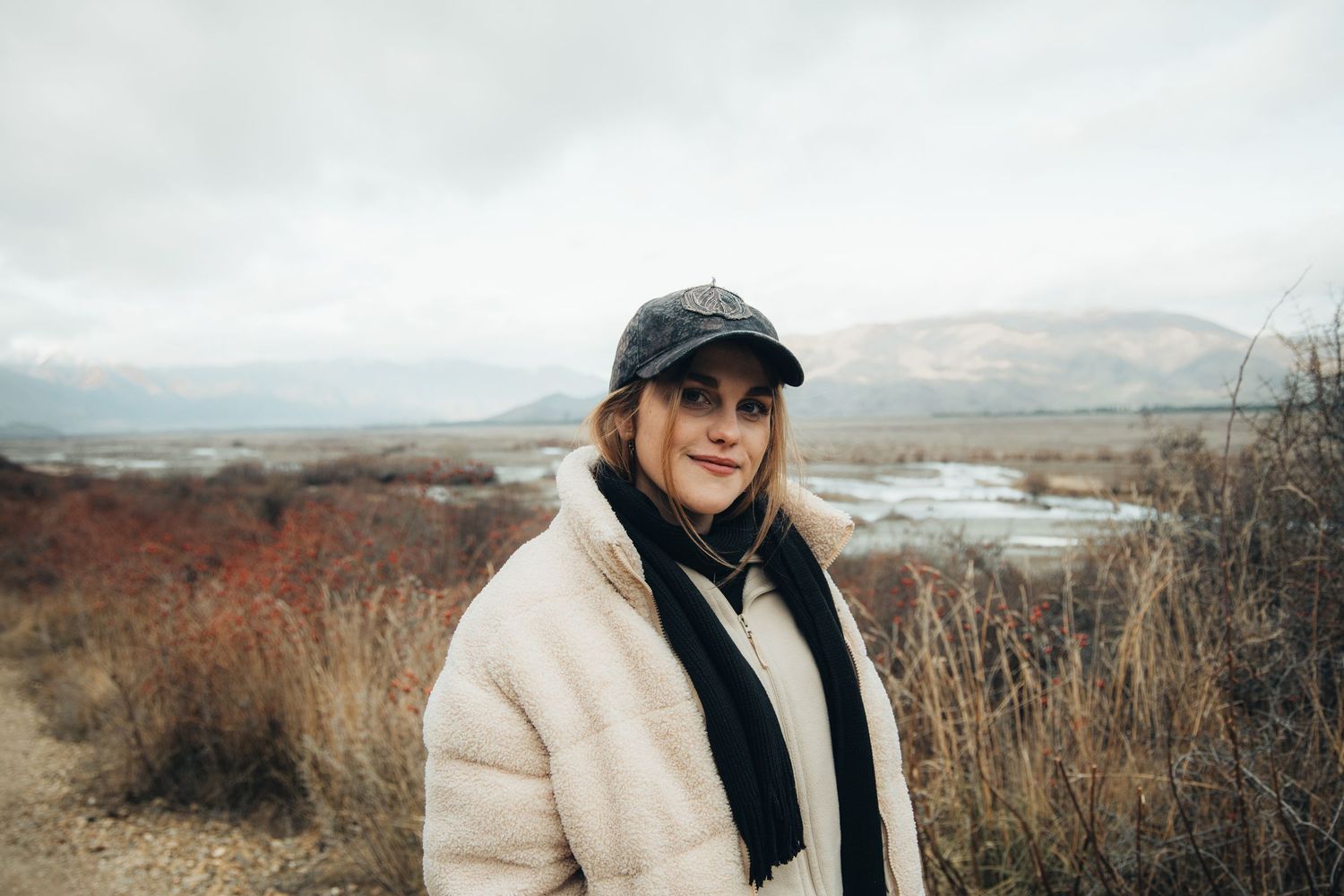 Person in winter coat enjoying scenic coastal views on cloudy day.
