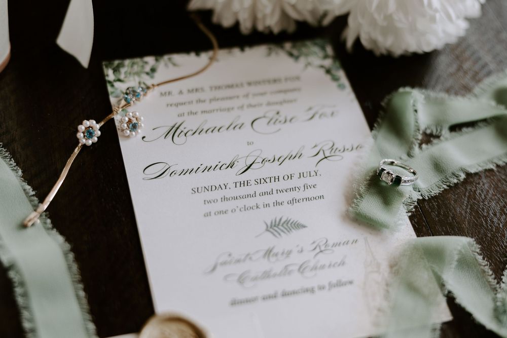 Close-up of floral wedding invitation for Michaela and Dominick with greenery details.