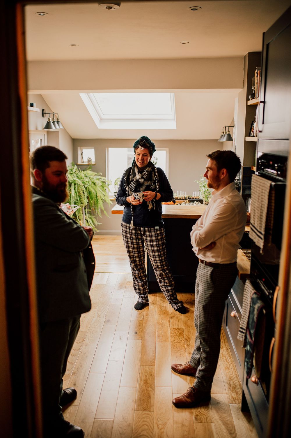 Three people stand in conversation on hardwood floors in a bright modern interior space.