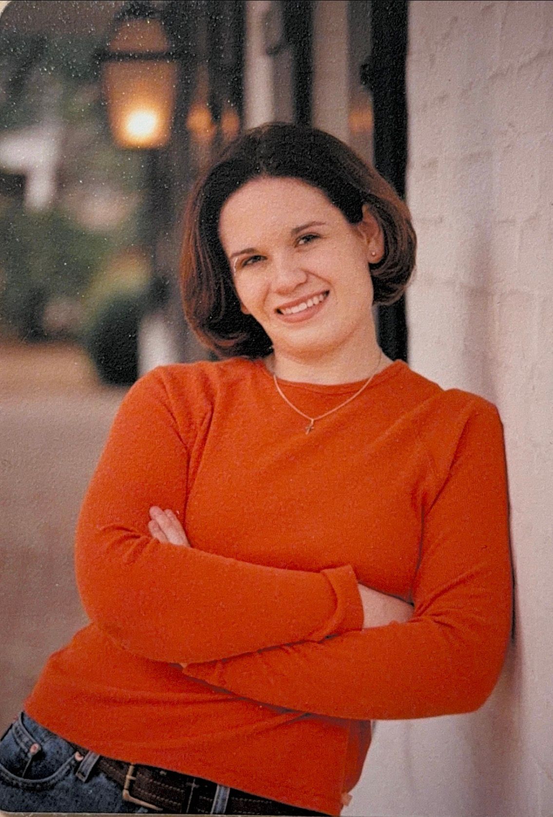 A person in a bright orange sweater poses against a light-colored wall in a series of casual portraits.