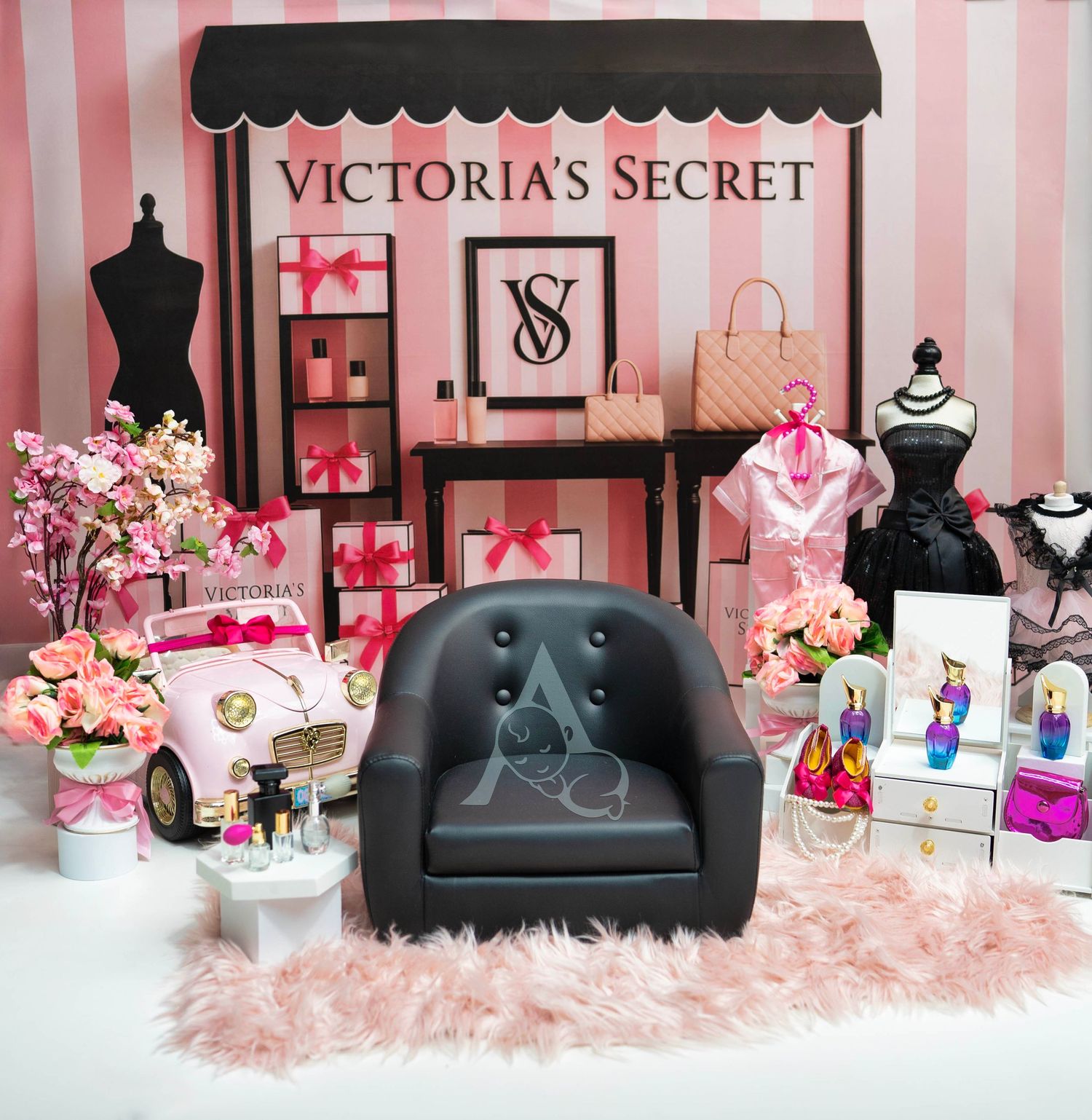 Miniature Victoria's Secret store display with pink striped backdrop, black chair, fashion accessories, flowers, and decorative items.