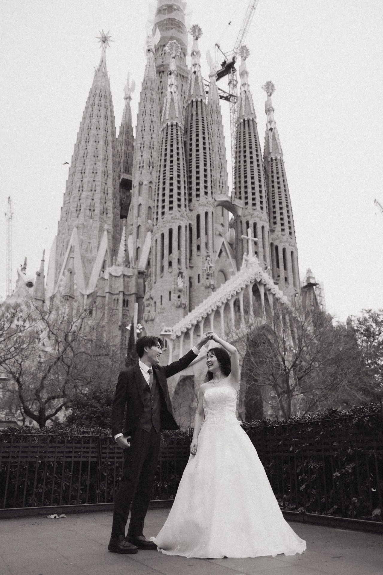 A wedding couple poses in front of the iconic Sagrada Familia cathedral in Barcelona, Spain.
