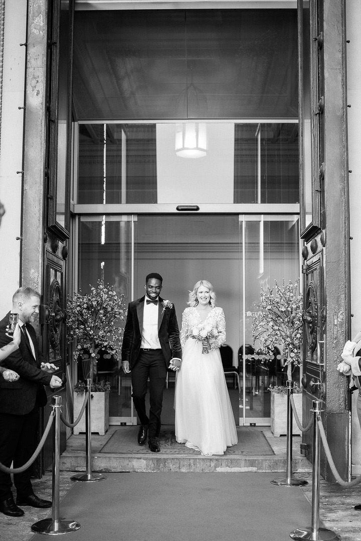 A series of black and white wedding photos showing people entering and exiting through a building's entrance.