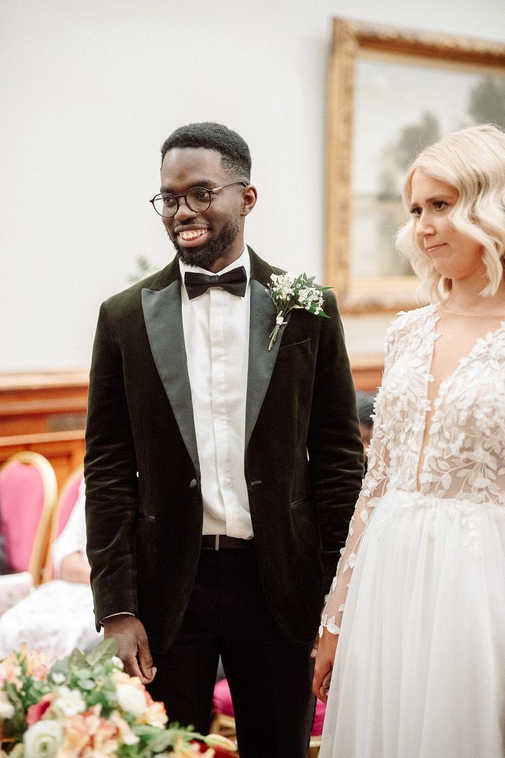 A happy couple shares a joyful moment during their wedding ceremony, with the groom in a classic black tuxedo.