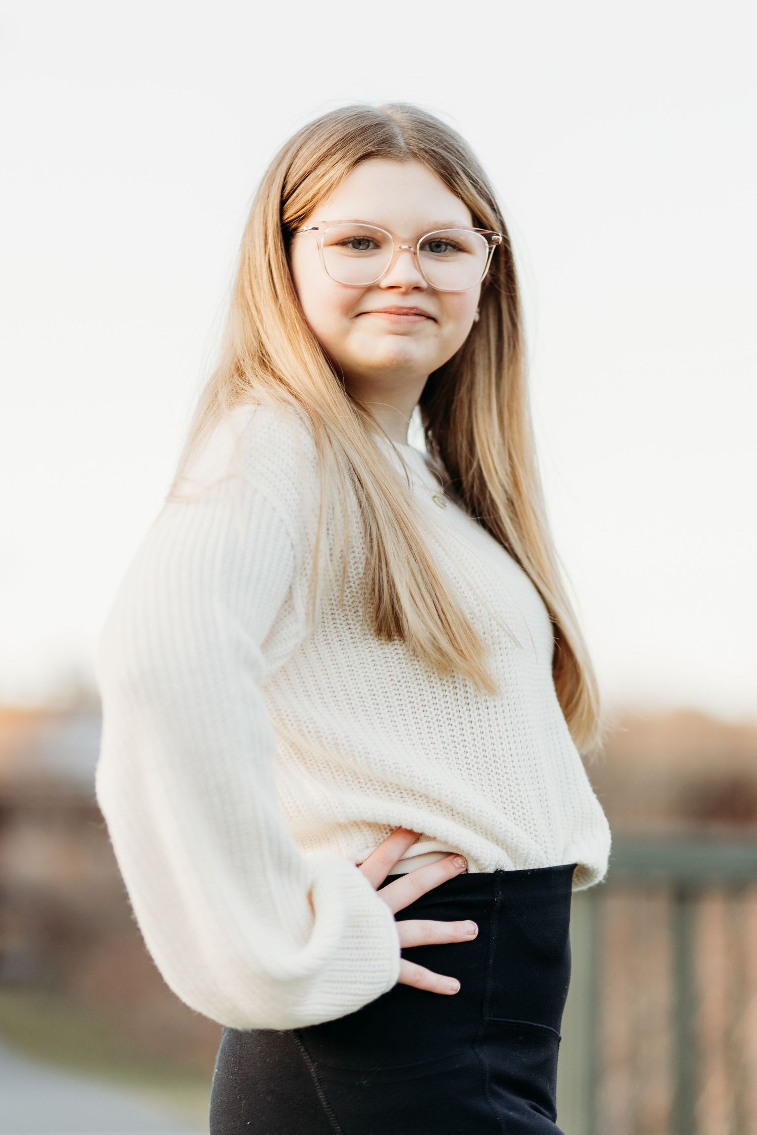 Person wearing white knit sweater and black pants poses outdoors against light background in multiple shots.