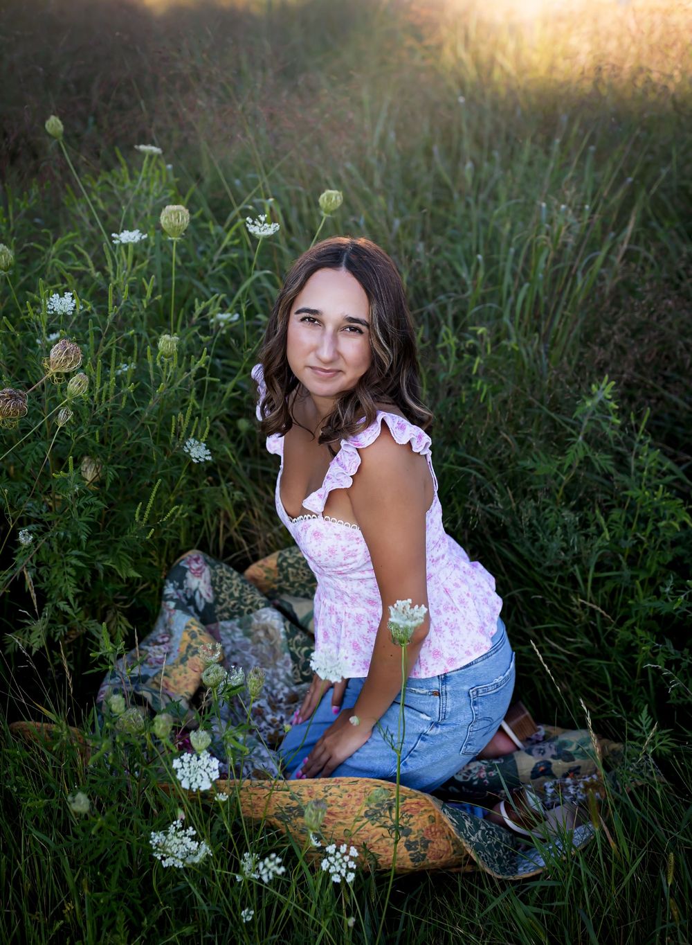 A dreamy summer photoshoot in a meadow with tall grass, dandelions, and golden sunlight at dusk.
