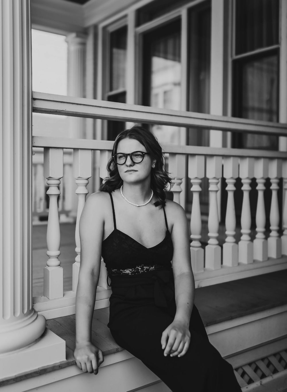 A black and white photo series shows someone in a black dress sitting on a porch railing with white columns.
