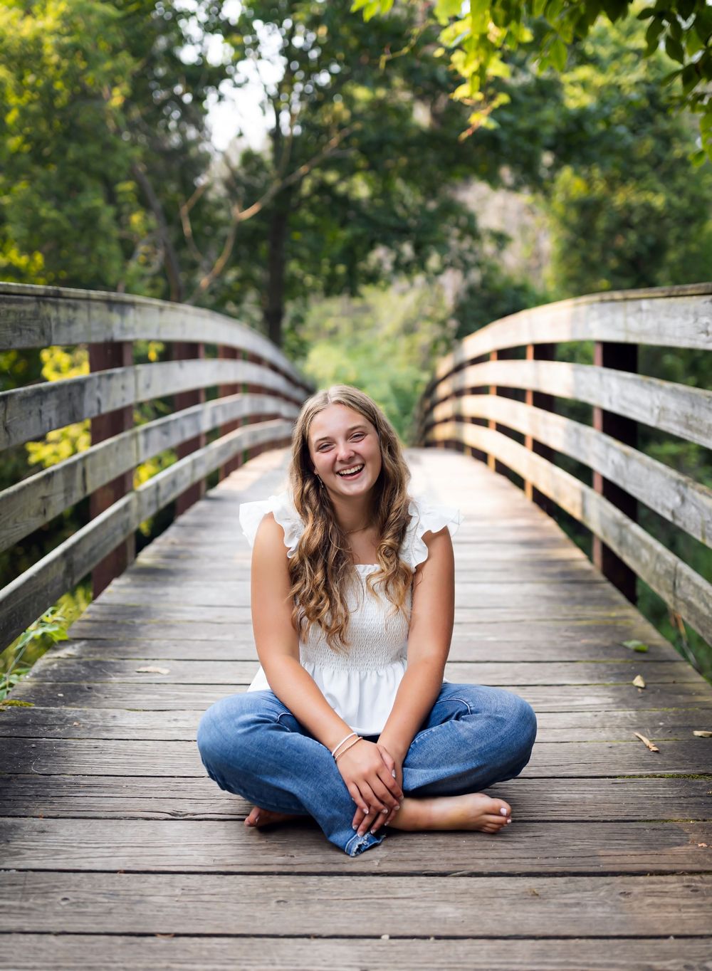 A sequence of casual portrait photos taken on a wooden bridge walkway surrounded by lush green foliage.