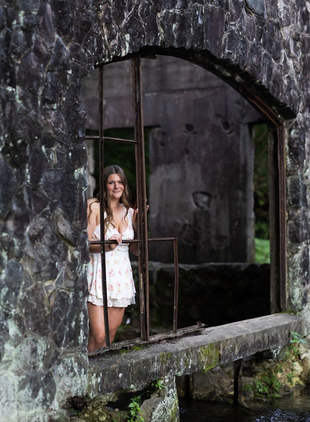 A person in white stands between stone pillars in a dark, abandoned building with dramatic lighting.