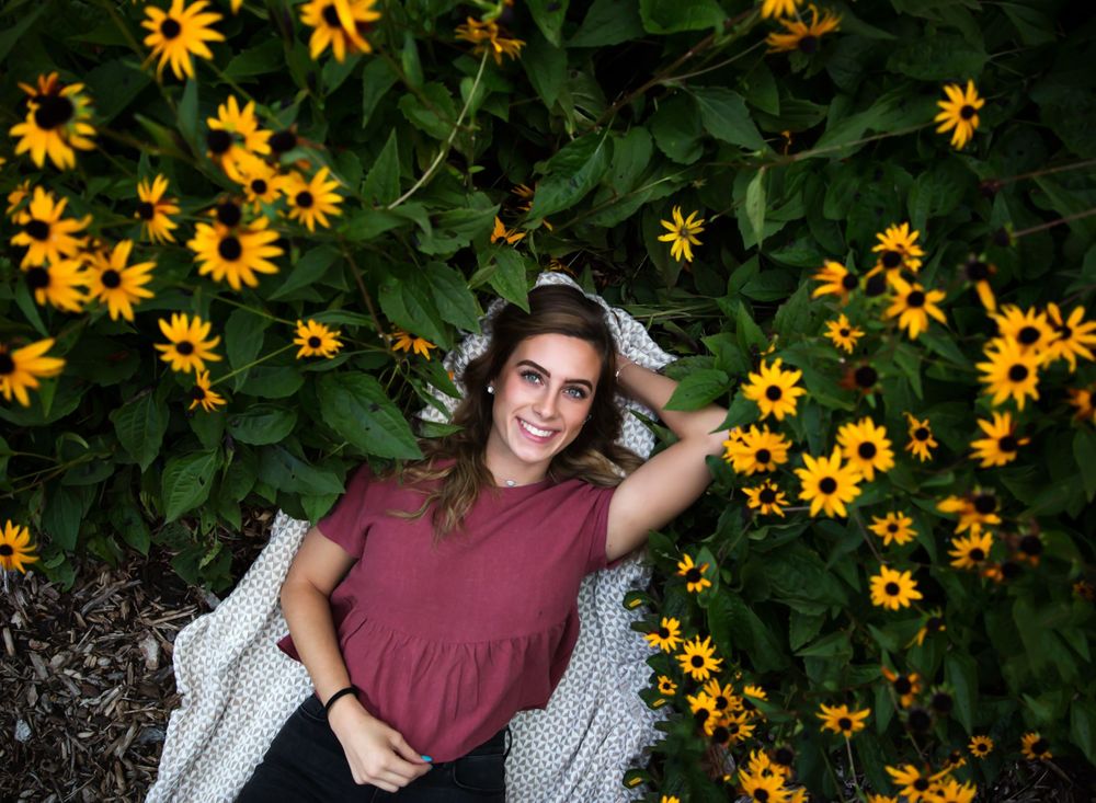 Senior photos in Waukesha, WI. Senior in high school is laying on the ground outside, surround by flowers.