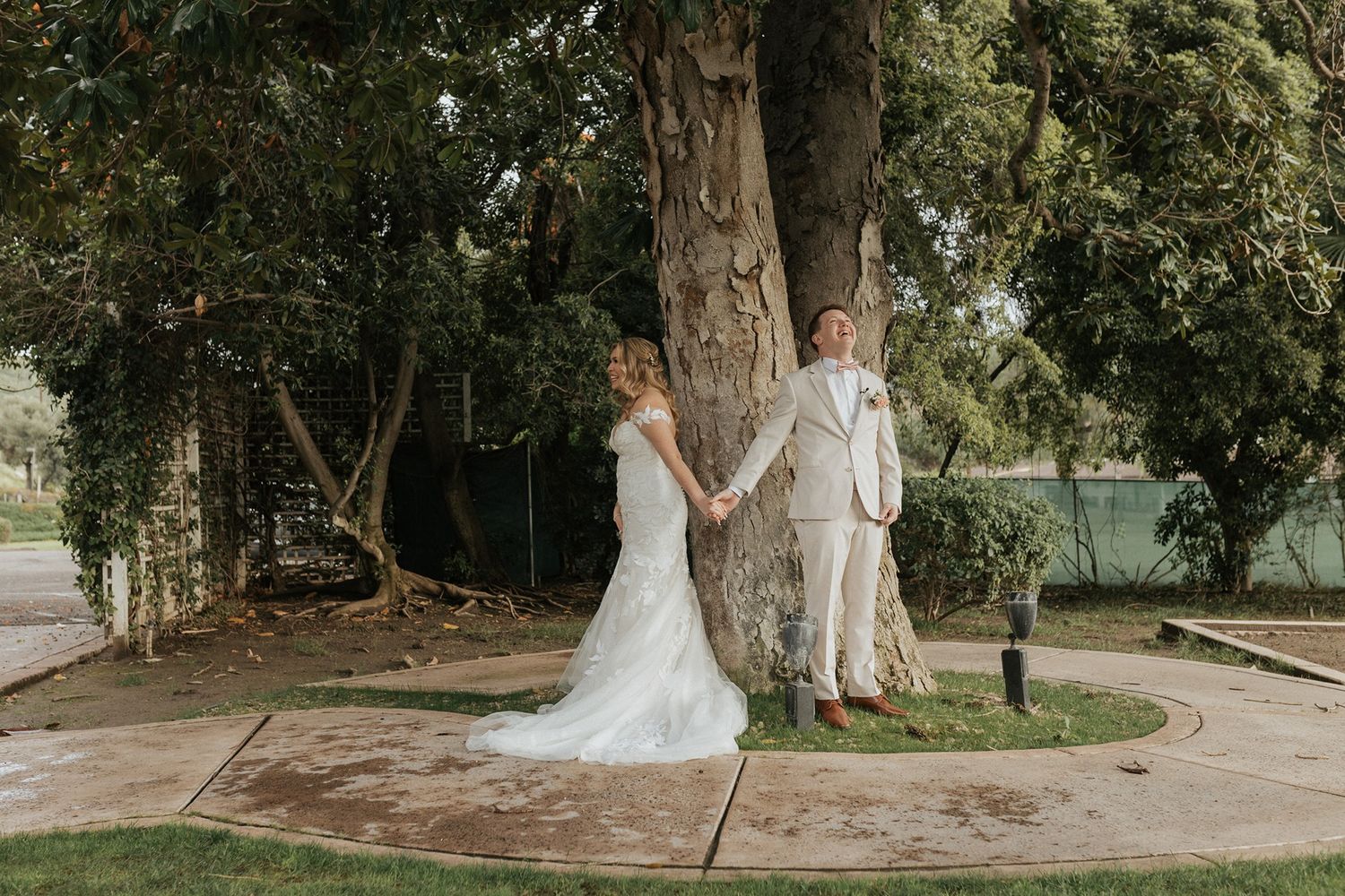 Couple in formal wedding attire stand together under a tree before their wedding ceremony at Singing Hills Golf Resort.