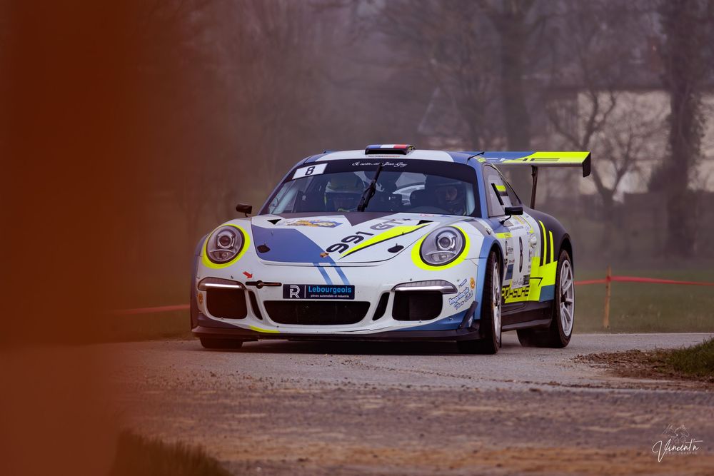 White Porsche 911 GT3 race cars compete on a professional racing circuit during an intense motorsport event.