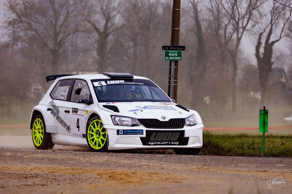 A white Skoda racing car with neon green wheels drifts through a misty forest road.