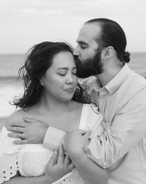 A romantic black and white photo series showing intimate moments between a couple embracing on a beach.